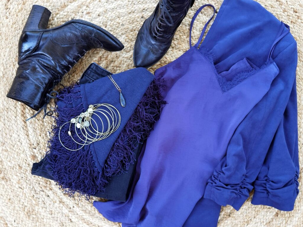 Stylish flat lay featuring black leather boots paired with a chic blue dress and stylish jewelry.