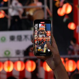A smartphone captures the colorful festival vibes in Shibuya, Tokyo at night.